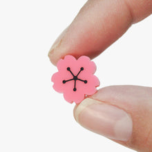 Load image into Gallery viewer, A close up of a pink plastic cherry blossom held between two fingers.
