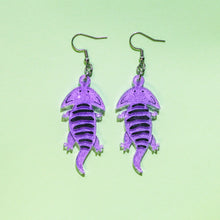 Load image into Gallery viewer, A pair of acrylic earrings of Diplocaulus, an extinct amphibian that lived long before the dinosaurs during the Permian in what is now North America and Africa. Diplocaulus looks like a salamander with a boomerang shaped head. The earrings are made from acrylic, a type of plastic and are light purple with glittery sparkles. There is some hand painted details, including the eyes and black stripes along the back.
