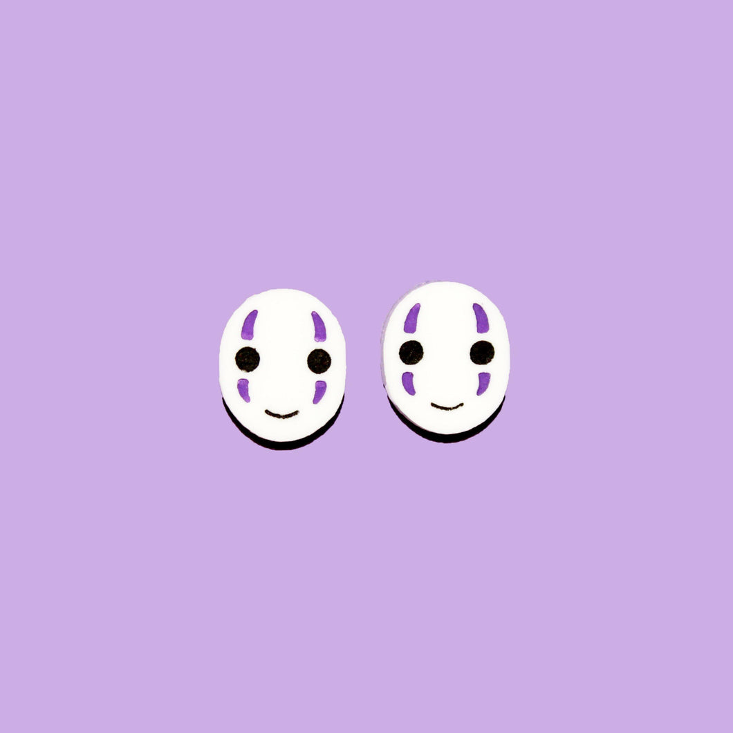 A pair earrings resembling two white masked faces with little smiles and purple streaks above and below each eye. Behind them is a purple background.