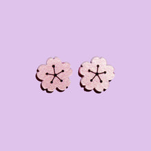 Load image into Gallery viewer, A pair of cute flower shaped earrings made from shimmery pale pink acrylic with a light purple background behind them.

