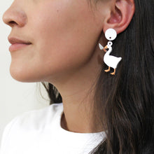 Load image into Gallery viewer, Side profile of a tan woman with dark brown hair in a white shirt. She&#39;s wearing a statement earring of a white goose wielding a large plastic knife.
