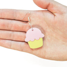 Load image into Gallery viewer, A hand facing upward holding a plastic earring of a delicious looking pastel coloured cupcake with pale pink coloured icing.
