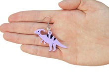 Load image into Gallery viewer, A close up of a hand in front of a white background holding a dinosaur earring. The earring is of a purple dinosaur. Specifically, it&#39;s of Parasaurolophus, a hadrosaur from the Late Cretaceous of what is now North America. The earring hangs from a silver-tone stainless steel earring hook.
