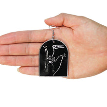 Load image into Gallery viewer, A close up of a dinosaur earring in a hand. The earring is a skeleton of the pterodactyl made from acrylic, a type of plastic. The charm is black, and the bones of the animal are in a transparent white. The earring is in the hand of a woman, in front of a white background.
