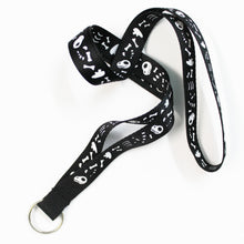 Load image into Gallery viewer, Photo of a black nylon lanyard featuring cartoon dinosaur bones in white. This lanyard does not have a plastic breakaway clasp. The design features bones from different parts of the body, including skull, head, claws, ribs, vertebrae, leg bones and pelvis. It&#39;s spoopy rather than spooky, the little skull looks like it&#39;s smiling.
