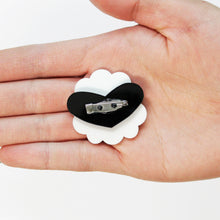 Load image into Gallery viewer, The backside of a sheep brooch in the palm of a hand. The brooch has a white fluffy ring with a black heart on top and then a stainless steel brooch clasp glued to the heart.
